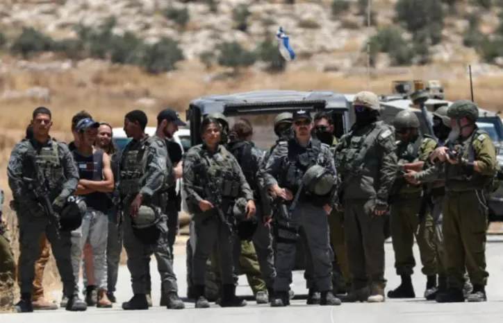Pasukan keamanan Israel mengambil tindakan di sepanjang jalan saat pemukim Yahudi Israel, yang dilindungi pasukan Israel, memblokir jalan menuju lahan pertanian Palestina di kota Izna, dekat Hebron di Tepi Barat.