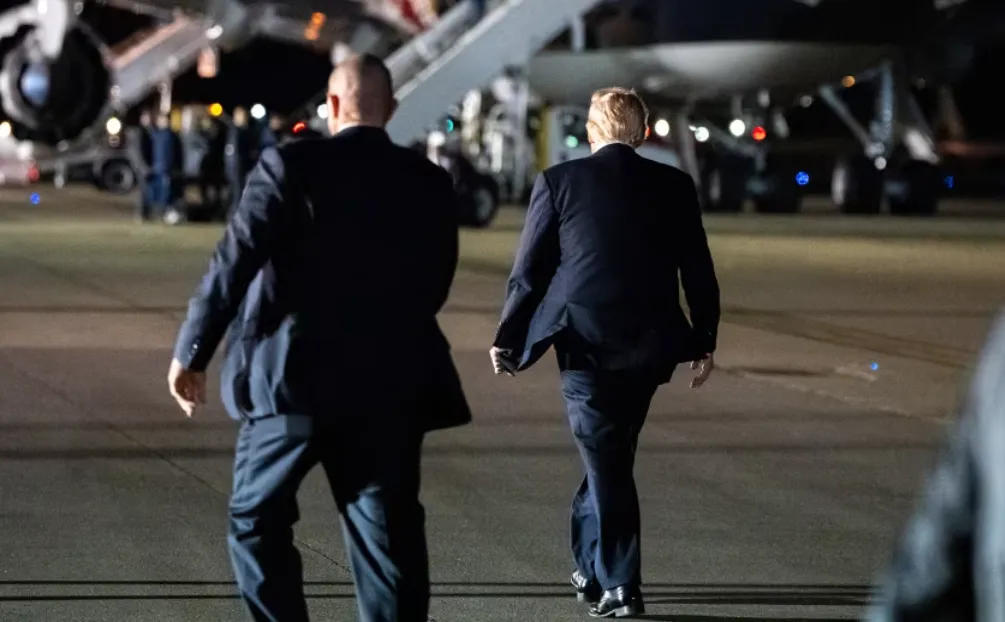 Presiden Trump menuju pesawat dengan dikawal petugas Secret Service.