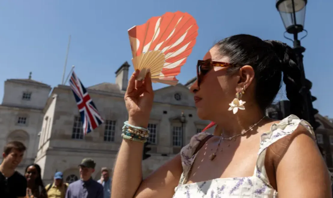 Seseorang melindungi wajahnya dari panas matahari menggunakan kipas tangan di London pada 25 Juni 2026, saat terjadi gelombang panas.