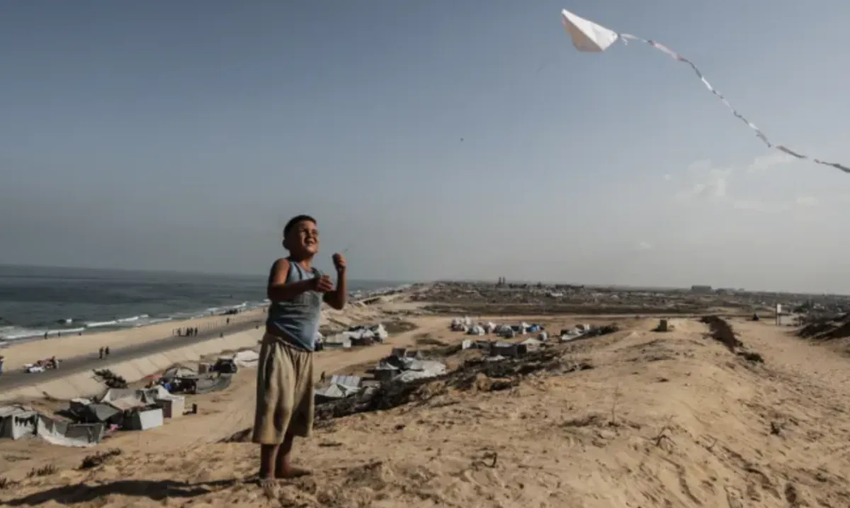 Seorang anak laki-laki menerbangkan layang-layang saat warga Palestina yang mengungsi dari serangan Israel berjuang untuk bertahan hidup di tenda darurat di Bukit Nuwairi, sebelah barat Gaza, pada 4 Oktober 2025.