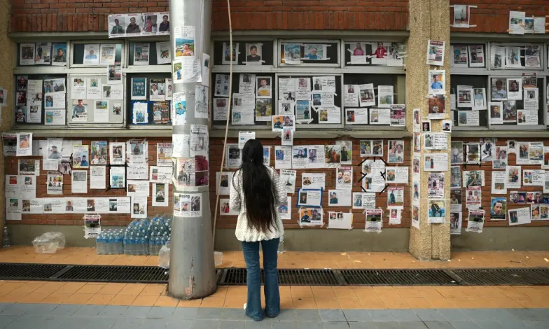 Seorang wanita berdiri di depan dinding yang memajang poster orang hilang di Kathmandu, Nepal pada hari Minggu, 30 Agustus.