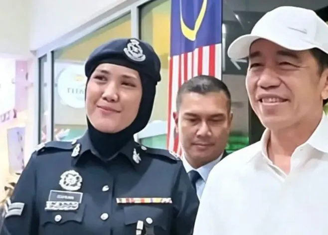 Jokowi berfoto bersama seorang petugas Malaysia.