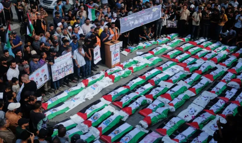 Para pelayat berkumpul di sekitar jenazah warga Palestina yang diselimuti bendera, yang baru-baru ini ditemukan dari reruntuhan.