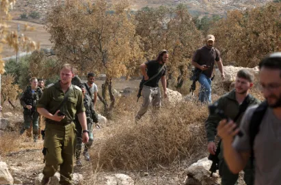Tentara Israel dan pemukim Israel bersenjata terlihat di kebun zaitun di kota Idhna, sebelah barat Hebron di Tepi Barat, Palestina.