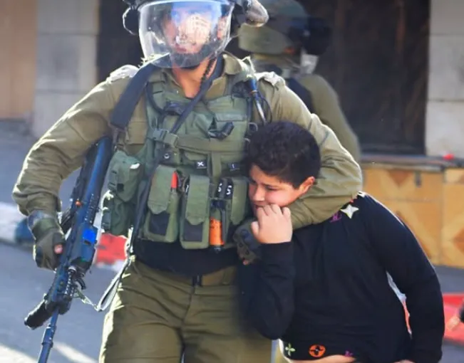 Tentara Zionis Israel membekuk anak Palestina. Kekerasan pada anak-anak sudah menjadi "standar" perilaku tentara Zionis.