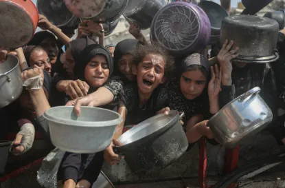 Warga Palestina yang kelaparan, termasuk perempuan dan anak-anak, memegang panci menunggu makanan yang dibagikan organisasi amal sementara Israel terus menghalangi bantuan kemanusiaan ke Jalur Gaza pada 10 Agustus 2025.