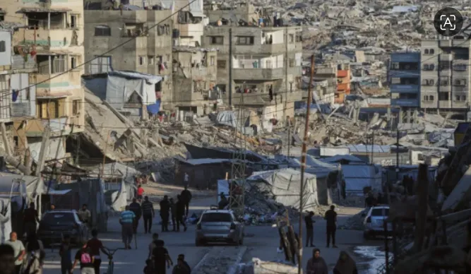 Warga Palestina berjalan di sepanjang jalan yang dikelilingi oleh bangunan yang hancur akibat serangan militer Israel di Kota Gaza, 6 Oktober 2026
