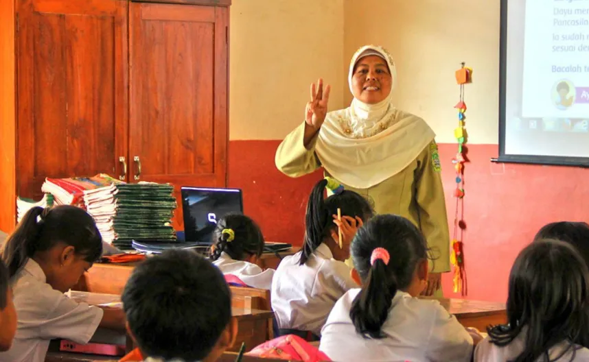 Ilustrasi guru sedang mengajar di kelas.
